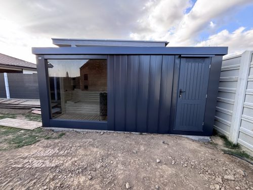 Exteriérová kombinovaná sauna SAIBOT s náraďovňou, zvonku je oplechovaná v bez údržbovom clippaneli, vnútorný obklad je osika biela, schodiskové lavice, 4x infra panel + ovládanie, soľná stena s LED podsvietením